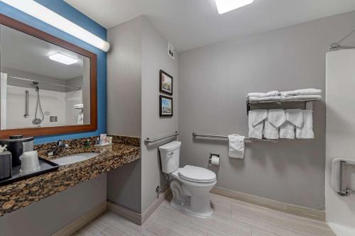 a bathroom with a toilet and a sink and a mirror at Garner Hotel Oklahoma City - Quail Springs by IHG in Oklahoma City