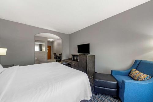 a hotel room with a bed and a blue chair at Garner Hotel Oklahoma City - Quail Springs by IHG in Oklahoma City
