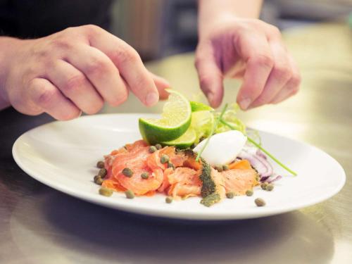 a person eating a plate of food on a table at Mercure Hotel Den Haag Central in The Hague