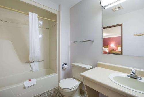 y baño con aseo, lavabo y bañera. en Econo Lodge Inn & Suites, en Escanaba