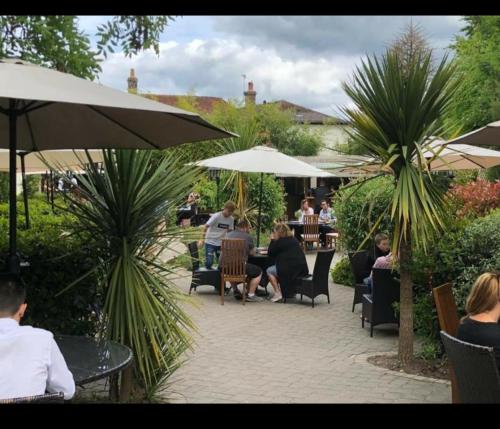 a group of people sitting around a patio with umbrellas at Greyhound Inn in Winterborne Kingston