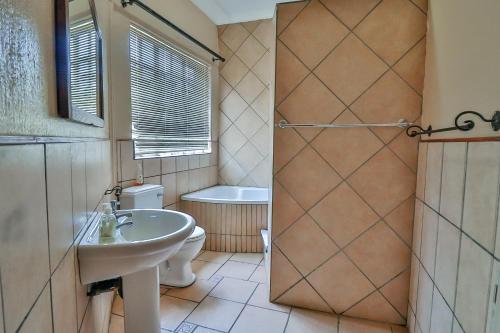 a bathroom with a sink and a toilet and a shower at Croc River Lodge in Komatipoort