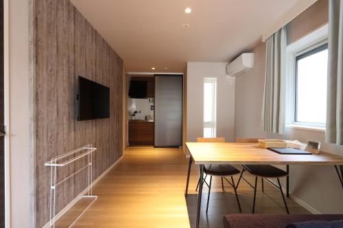 a dining room with a table and a television on a wall at 5 minutes Shin-Osaka 9 in Osaka