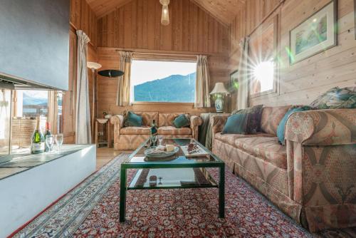 a living room with a couch and a table at Chalet Hibou, large chalet with mountain views and close to slopes in Saint-Chaffrey