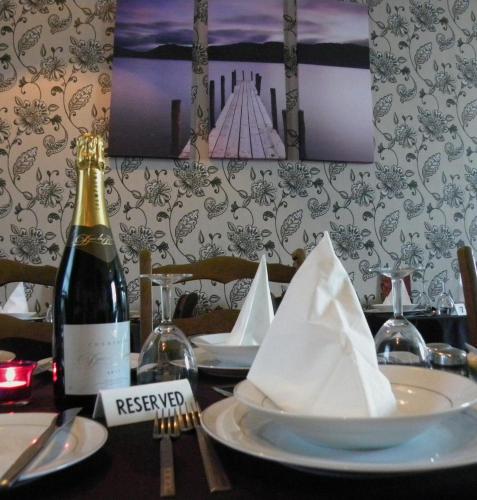 a table with a bottle of wine and a plate with a napkin at The Davron Hotel in Fraserburgh