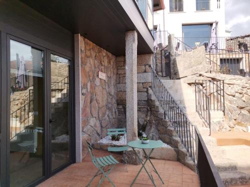 a patio with a table and a stone wall at Carrioza Alojamiento Turístico in Parada del Sil