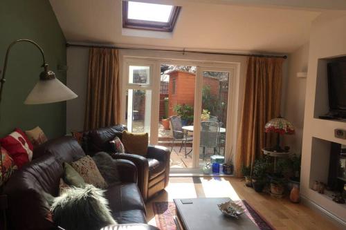 a living room with a couch and a sliding glass door at Potters Court A Hidden Gem in Tewkesbury