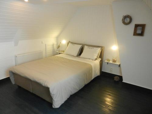 Schlafzimmer mit einem Bett mit weißer Bettwäsche und Kissen in der Unterkunft Holiday Home Juliette in Poperinge