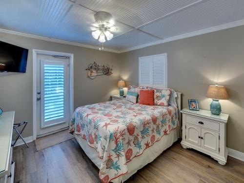 ブレイデントン・ビーチにあるIdeal beach hideaway pool condo located between the island marina and beachのベッドとランプ付きのテーブルがある寝室