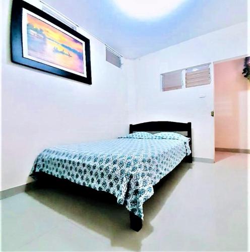 a bed in a white room with a picture on the wall at El Paititi Hotel in Iquitos