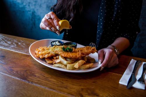 a woman is holding a plate of food on a table at Katch in Northallerton