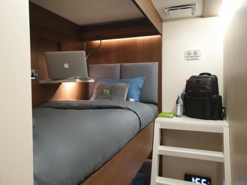 ein Schlafzimmer mit einem Bett und einem Laptop darauf in der Unterkunft sleep 'n fly Sleep Lounge, C-Gates Terminal 3 - TRANSIT ONLY in Dubai