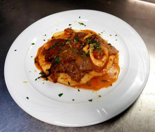a white plate of food with meat and sauce at RistHotel Pianura Inn in Busnago