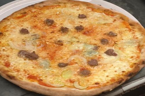 a pizza sitting on top of a white plate at RistHotel Pianura Inn in Busnago