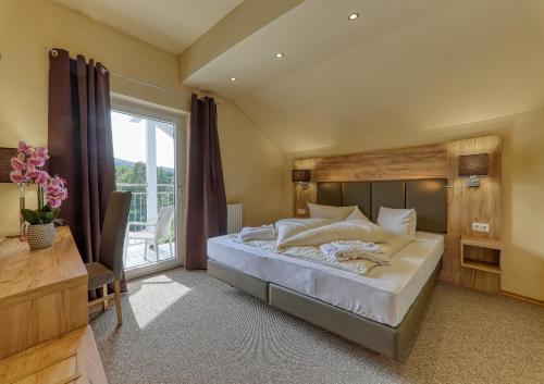 a bedroom with a large bed and a large window at Wellnesshotel deine Auszeit, Adults only in Achslach