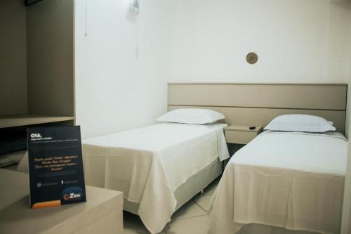 a room with two beds and a sign in it at Zen Pousada in Telêmaco Borba