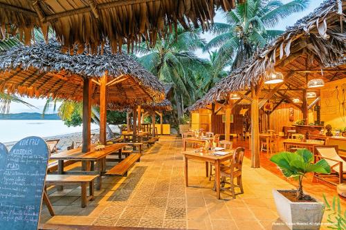 un restaurante en la playa con mesas y sombrillas de paja en Sambatra Bed and Breakfast, en Ambaro