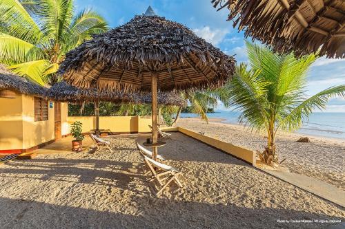 a straw umbrella and chairs on a beach at Sambatra Bed and Breakfast in Ambaro