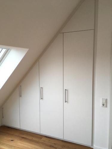 a row of white cabinets in a loft at RaumAusbeute Design Apartment Hoher Priester in Detmold