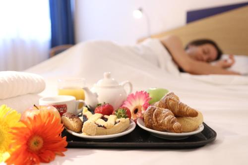 a tray of breakfast foods on a bed with a person sleeping at Park Hotel Sant'Elia in Fasano