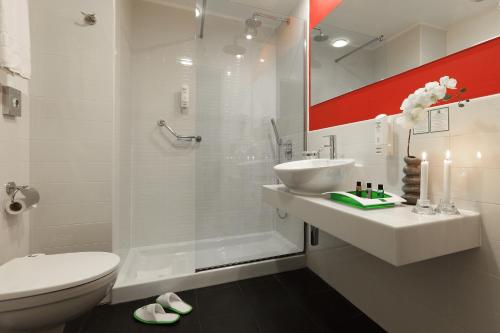 uma casa de banho com um chuveiro, um lavatório e um WC. em Holiday Inn Genoa City, an IHG Hotel em Génova