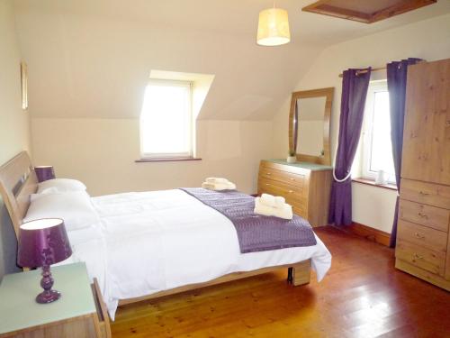 a bedroom with a white bed and a mirror at Allaghee Mor St Finians Bay in Ballinskelligs