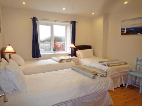 three beds in a room with a window at Fourteens Holiday Home Ballinskelligs in Ballinskelligs