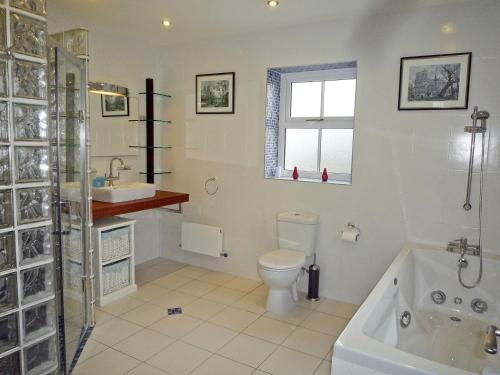 a bathroom with a tub and a toilet and a sink at Fourteens Holiday Home Ballinskelligs in Ballinskelligs