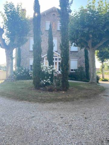 un gran edificio con árboles delante de él en Chambres privées dans maison avec grand parc et piscine proche Via Rhona, en Andancette