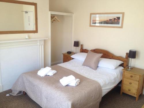 a bedroom with a bed with two towels on it at Arcadia Guest House in Weymouth