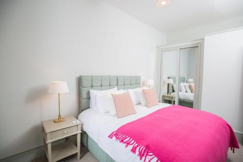a bedroom with a large bed with a pink blanket at 50 London Road - By Luxury Apartments in Cheltenham