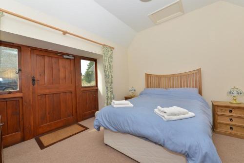 Un dormitorio con una cama azul con toallas. en Willows, en Calbourne