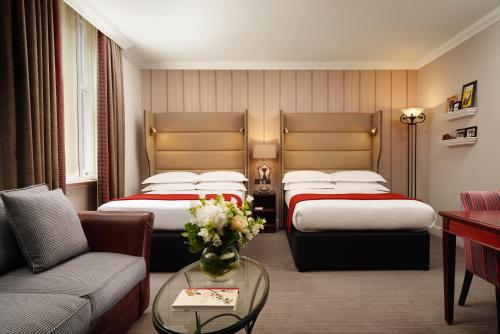 a hotel room with two beds and a couch at The Bailey's Hotel London Kensington in London
