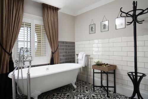 a white bathroom with a tub and a window at The Bailey's Hotel London Kensington in London
