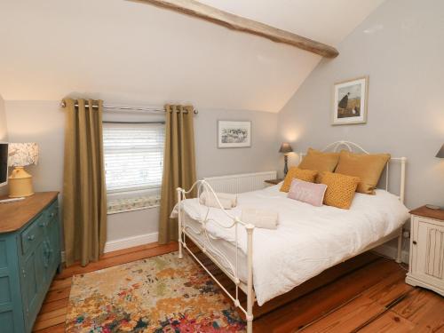 a bedroom with a white bed and a window at Millstream Cottage in Castleton
