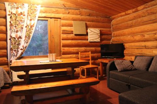 eine Blockhütte mit einem Tisch und einem Sofa in der Unterkunft Cottages RukaTupa in Ruka