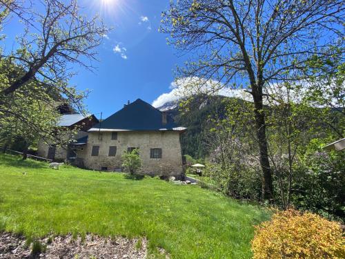 a stone house on a hill with a green field at Maison d’hôtes les Méans in Méolans