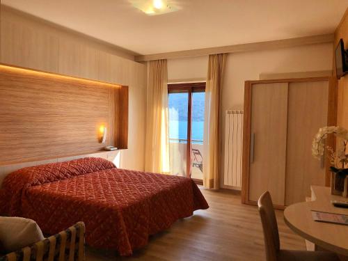 a hotel room with a red bed and a table at Hotel Palazzina in Gargnano