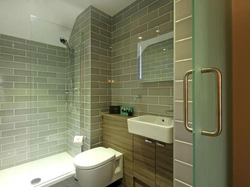 a bathroom with a toilet and a sink and a shower at Harlech Apartments - Efnisien in Harlech