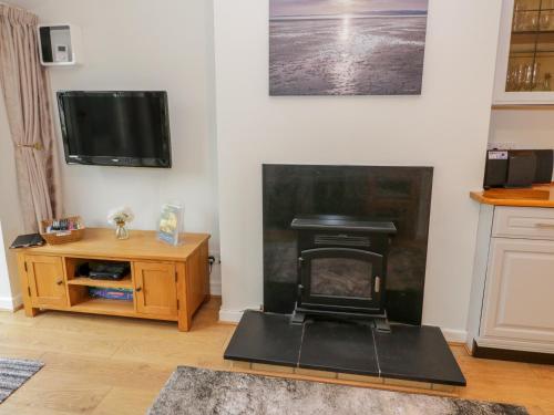 a living room with a fireplace and a tv at Bwthyn in Moelfre