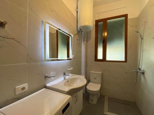 a white bathroom with a sink and a toilet at Trumpets Apartment in Tirana