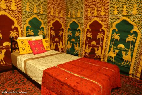 a bedroom with a bed in a room withpainted walls at Ouzina Desert Camp in Ouzina