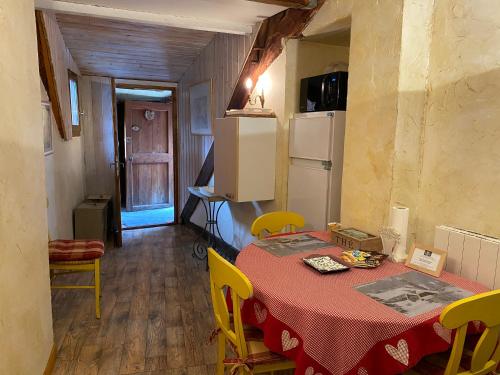 a kitchen with a table with yellow chairs and a refrigerator at Maison d’hôtes les Méans in Méolans