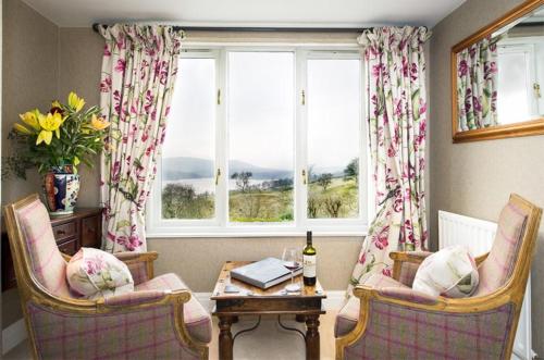 a living room with two chairs and a table and a window at Holbeck Ghyll Country House Hotel with Stunning Lake Views in Windermere