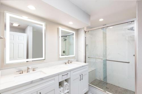 Westgate Branson Lakes Resort في Hollister: حمام أبيض مع مغسلتين ودش زجاجي
