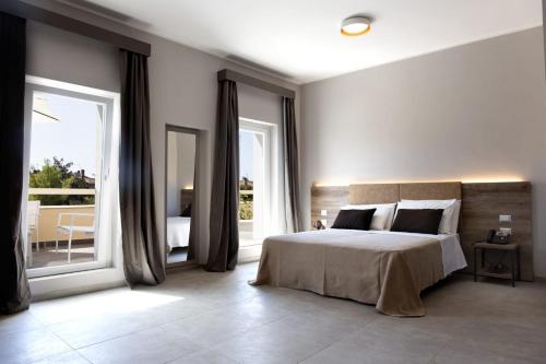 a bedroom with a large bed and a balcony at Hotel San Vincenzo Resort in Policoro
