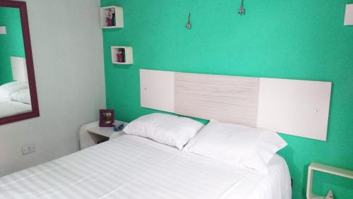 um quarto com uma parede verde e uma cama branca em Casa Confortavel Paraty em Paraty