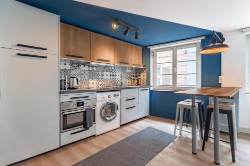 une cuisine avec des murs bleus et une table en bois dans l'établissement Appartements de la Pléiade, à Strasbourg