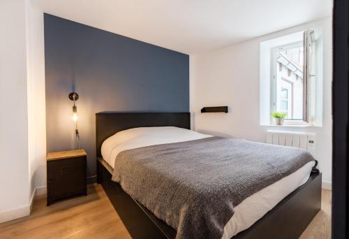 - une chambre avec un grand lit et un mur bleu dans l'établissement Appartements de la Pléiade, à Strasbourg