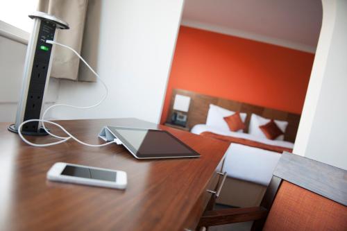 a desk with a computer on it with a bed at Conference Aston Hotel - Birmingham City in Birmingham